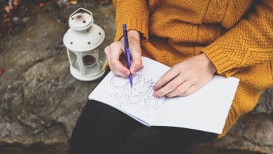 A girl holding a pencil near her sketchbook thinking What to Draw When I Don't Know What to Draw