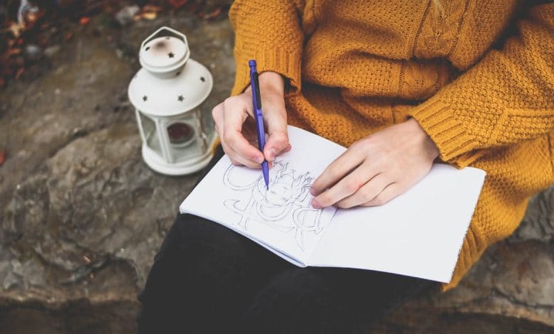 A girl holding a pencil near her sketchbook thinking What to Draw When I Don't Know What to Draw